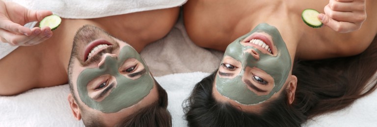 Image of Happy couple enjoying facial treatment procedure in spa salon, above view. Banner design