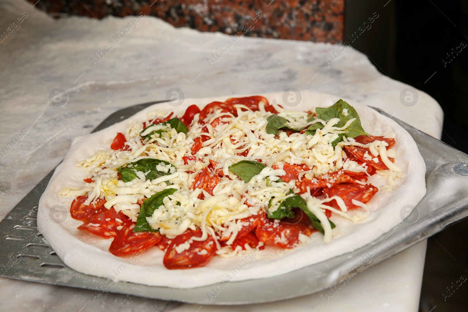 Photo of Peel with raw traditional Italian pizza on table in restaurant kitchen