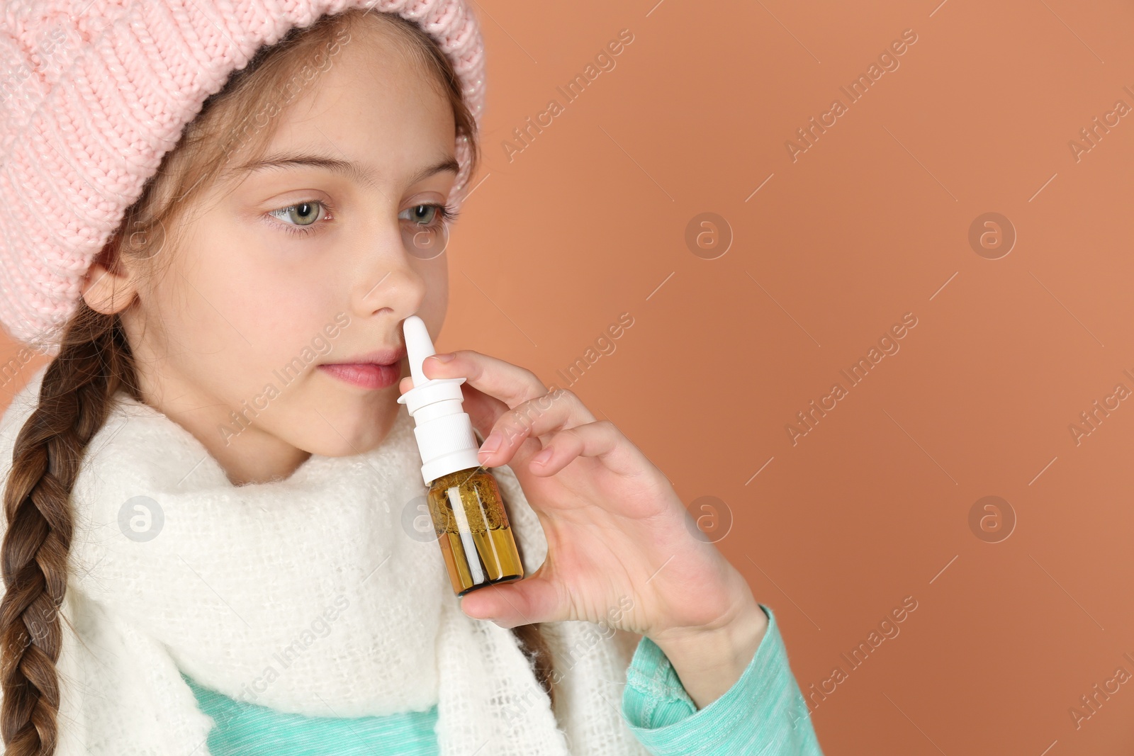 Photo of Sick little girl using nasal spray on coral background. Space for text