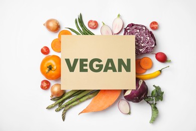 Image of Paper card with word Vegan and fresh vegetables on white background, flat lay