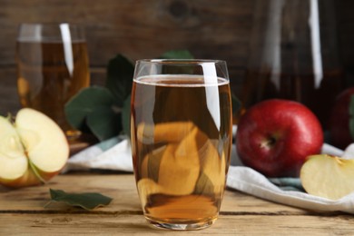 Photo of Glass of delicious apple cider on wooden table