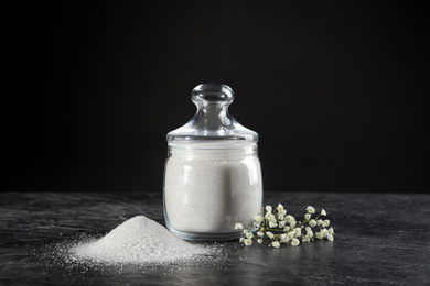 Bowl with granulated sugar and flowers on black table