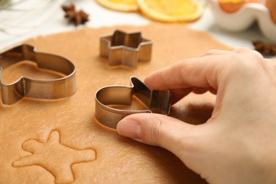 Photo of Woman cutting dough with cookie cutter at table, closeup. Christmas biscuits