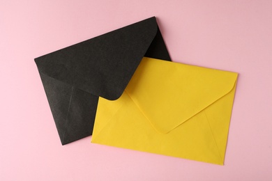 Colorful paper envelopes on pink background, top view