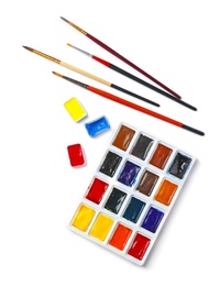 Photo of Plastic palette with colorful paints and brushes on light background, top view