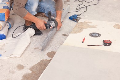 Worker using saw with circular diamond blade for metal stud cutting indoors, closeup. Tiles installation process