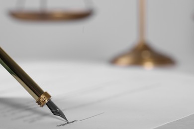 Signing document with fountain pen at table, closeup and space for text. Notary contract