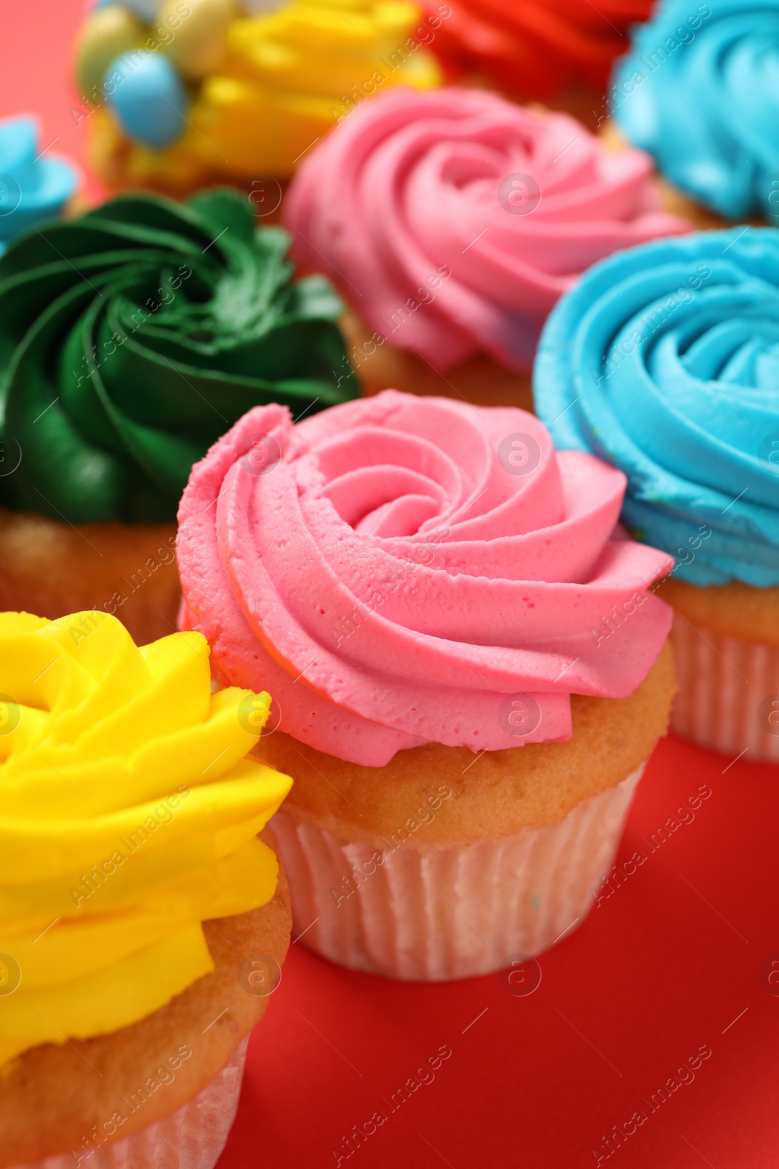 Photo of Delicious cupcakes with bright cream on red background, closeup