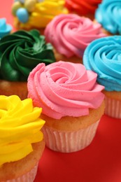 Photo of Delicious cupcakes with bright cream on red background, closeup