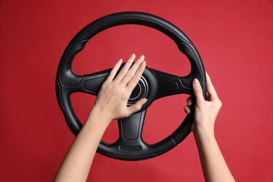 Photo of Woman holding steering wheel on red background, closeup