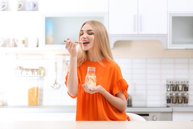 Photo of Young woman with yogurt in kitchen