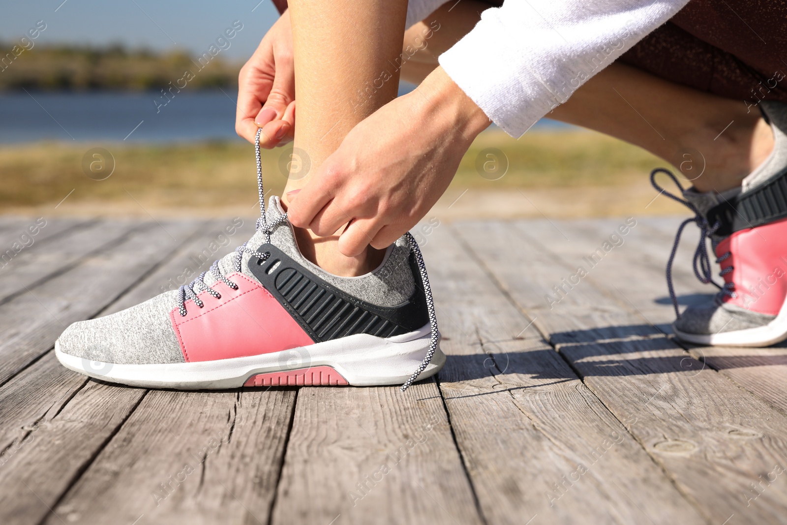 Image of Sporty woman tying shoelaces outdoors on sunny morning, closeup