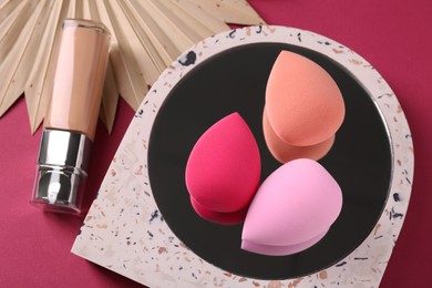 Stylish presentation of makeup sponges and skin foundation on pink background, above view