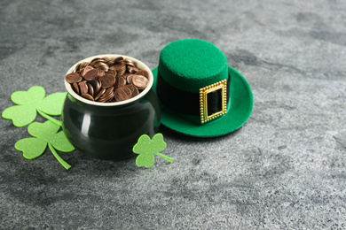 Photo of Pot of gold coins, hat and clover leaves on grey stone table. St. Patrick's Day celebration