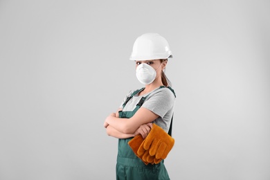 Female industrial worker in uniform on light background. Safety equipment