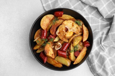 Delicious baked potato with thin dry smoked sausages, onion and dill in bowl on gray table, top view