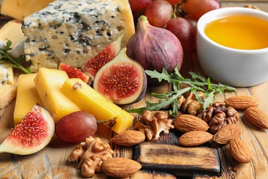 Set of different snacks with ripe figs served on wooden table, closeup