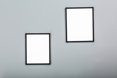 Photo of Frames with empty canvases on wall in modern art gallery. Mockup for design