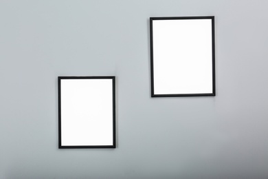 Frames with empty canvases on wall in modern art gallery. Mockup for design