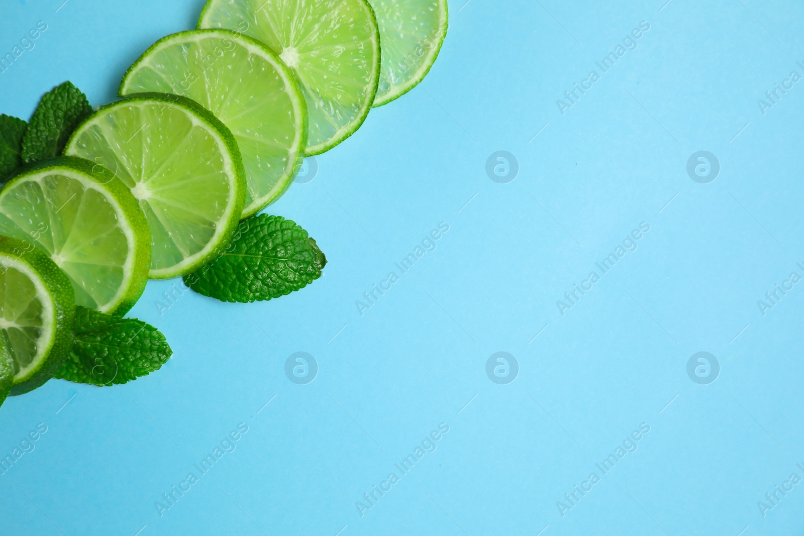 Photo of Slices of fresh juicy lime and mint on blue background, flat lay. Space for text