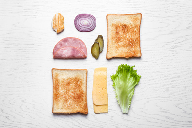 Fresh ingredients for tasty sandwich on white wooden background, flat lay