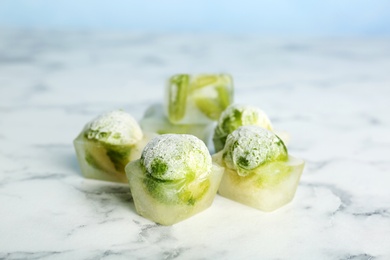 Photo of Brussels sprouts in ice cubes on table. Frozen vegetables