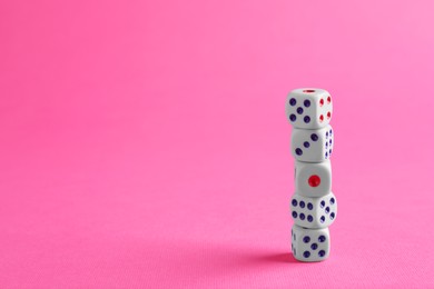Photo of Many stacked game dices on pink background. Space for text