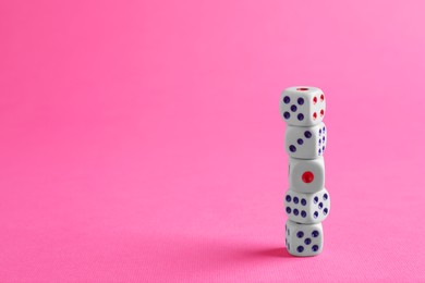 Many stacked game dices on pink background. Space for text