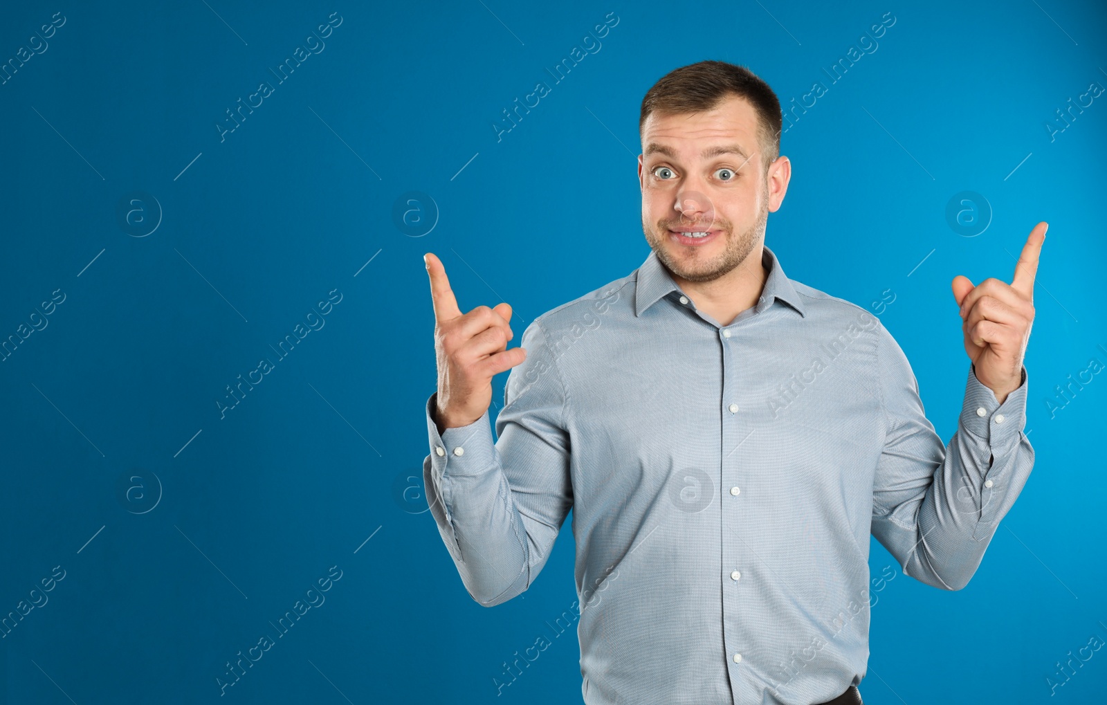 Photo of Portrait of emotional young man on blue background. Space for text