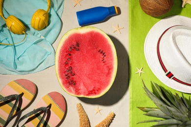 Flat lay composition with watermelon and beach accessories on sand