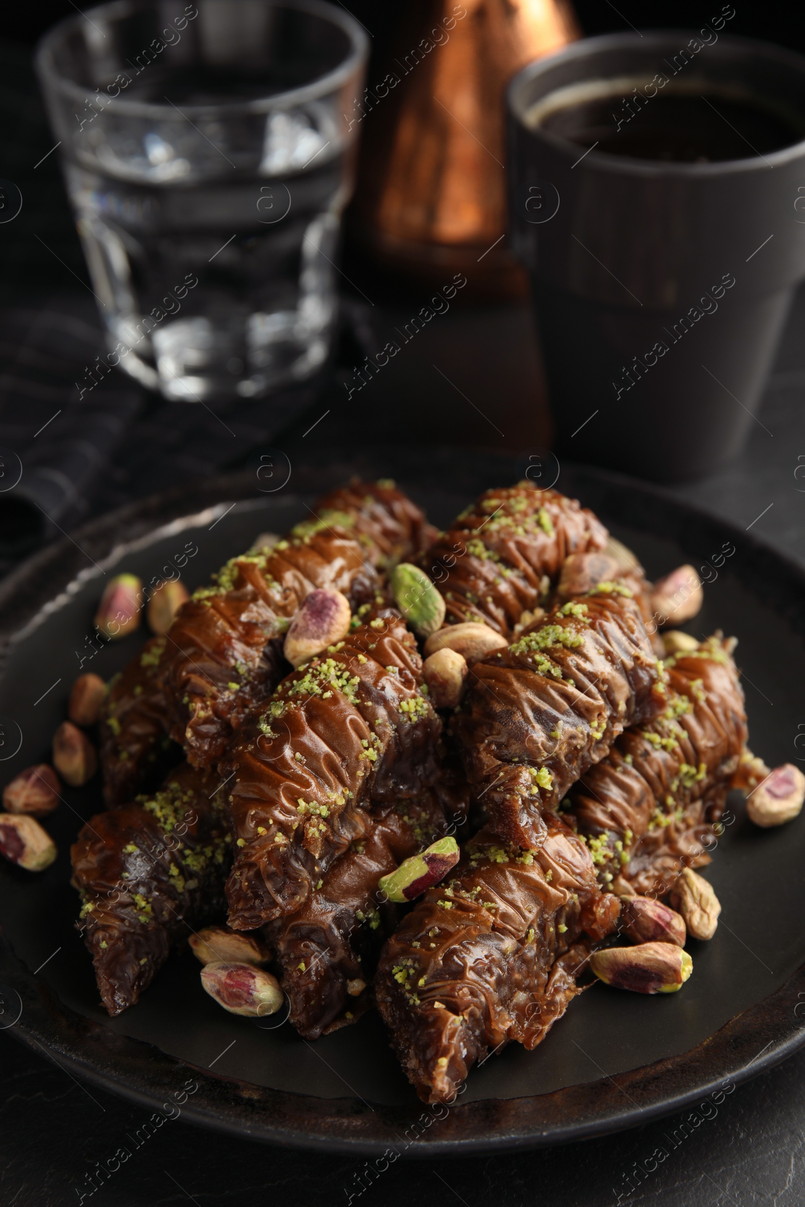 Photo of Delicious baklava with pistachio nuts on black table
