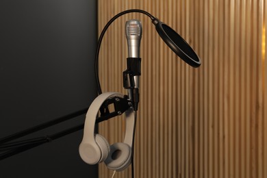 Photo of Stand with microphone, headphones and pop filter indoors. Sound recording and reinforcement