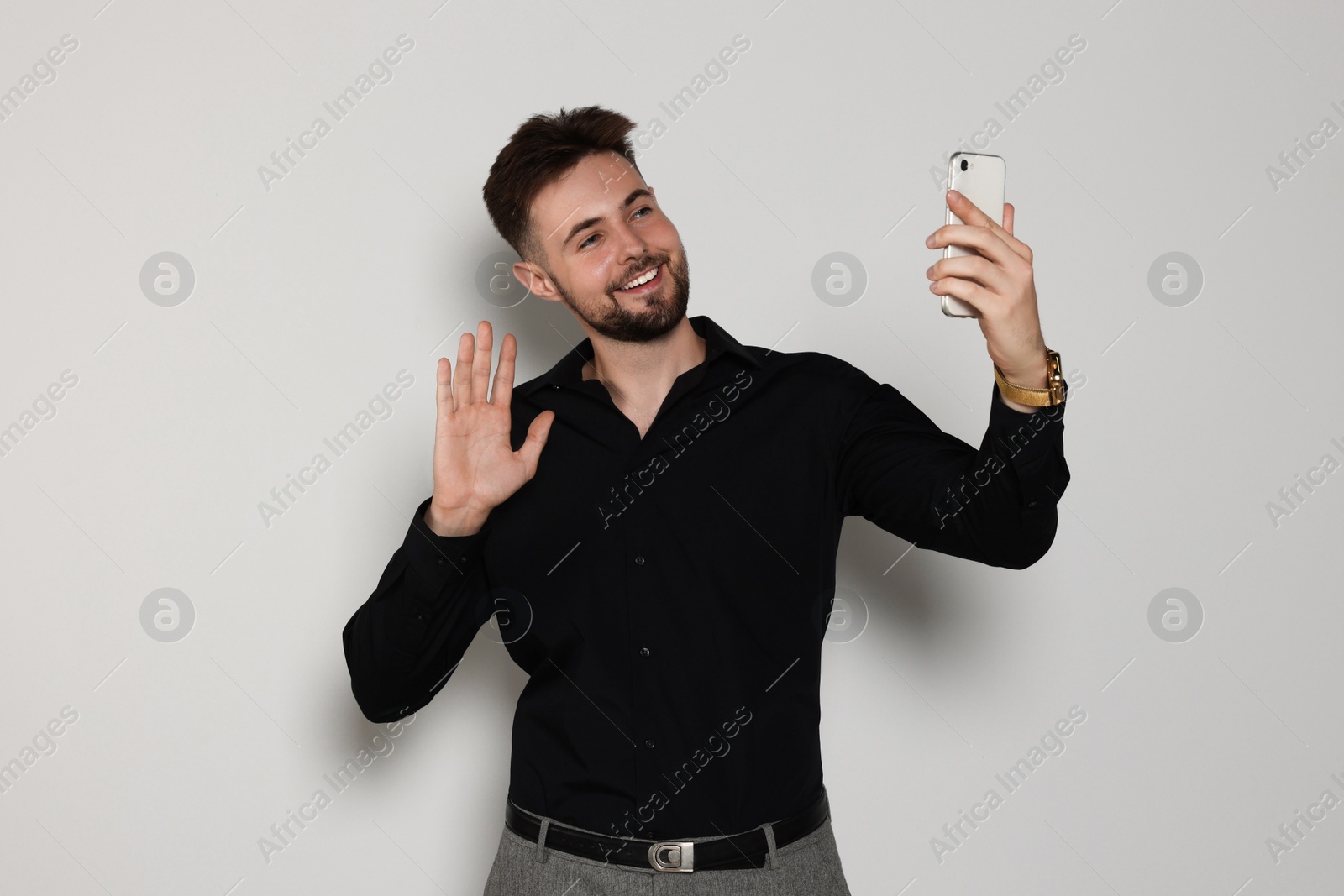 Photo of Handsome man in black shirt with phone on light grey background