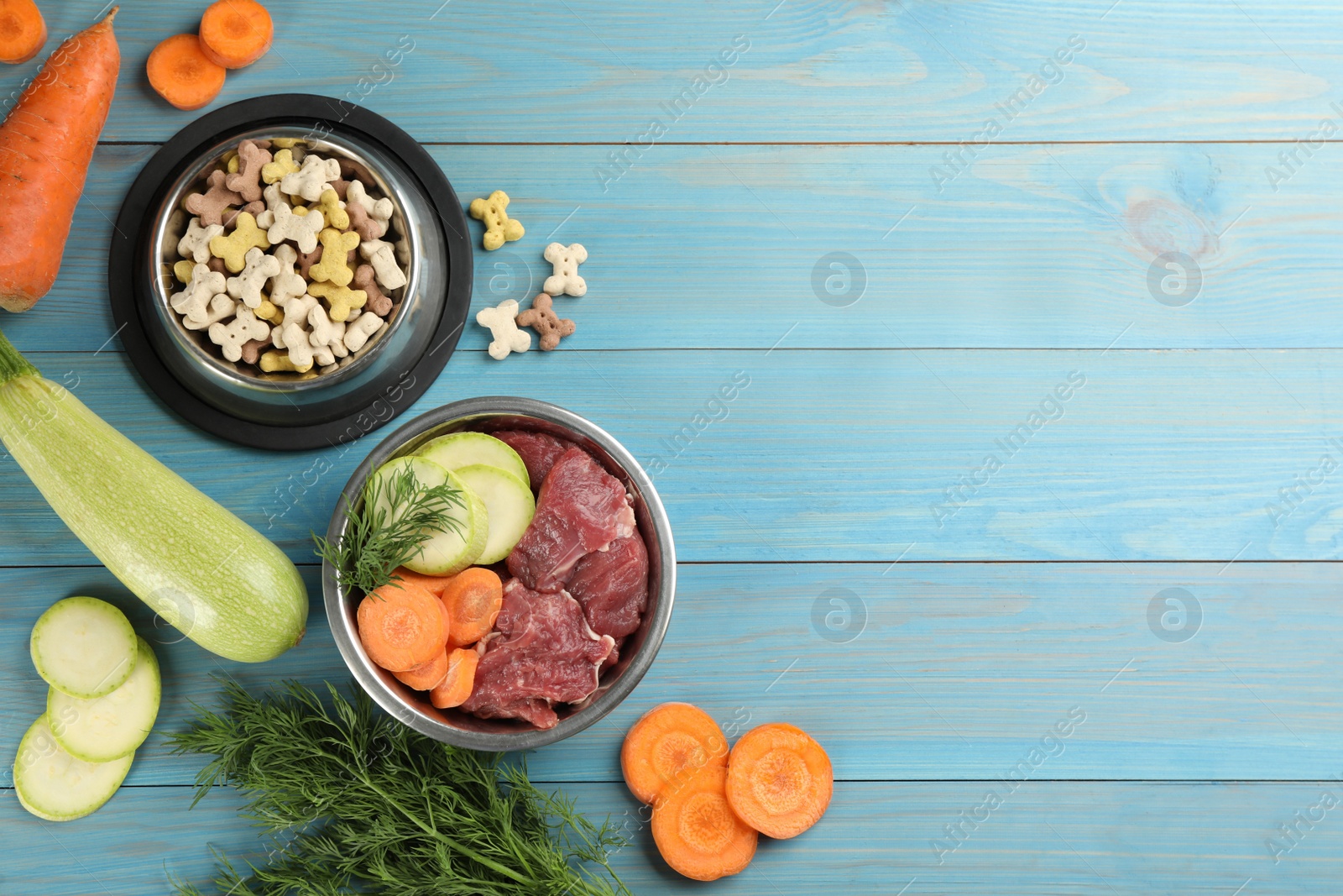 Photo of Pet food and natural ingredients on light blue wooden table, flat lay. Space for text