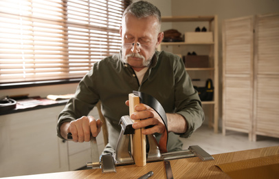 Man working with leather belt at table in atelier