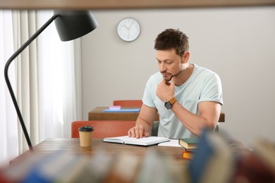 Man reading book at table in library