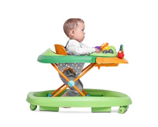 Photo of Cute little boy making first steps with baby walker on white background
