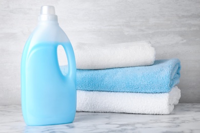 Bottle of laundry detergent and towels on marble table, space for text