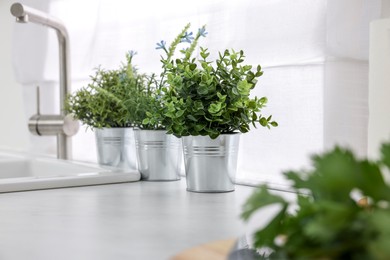 Different potted artificial plants on countertop in kitchen. Home decor