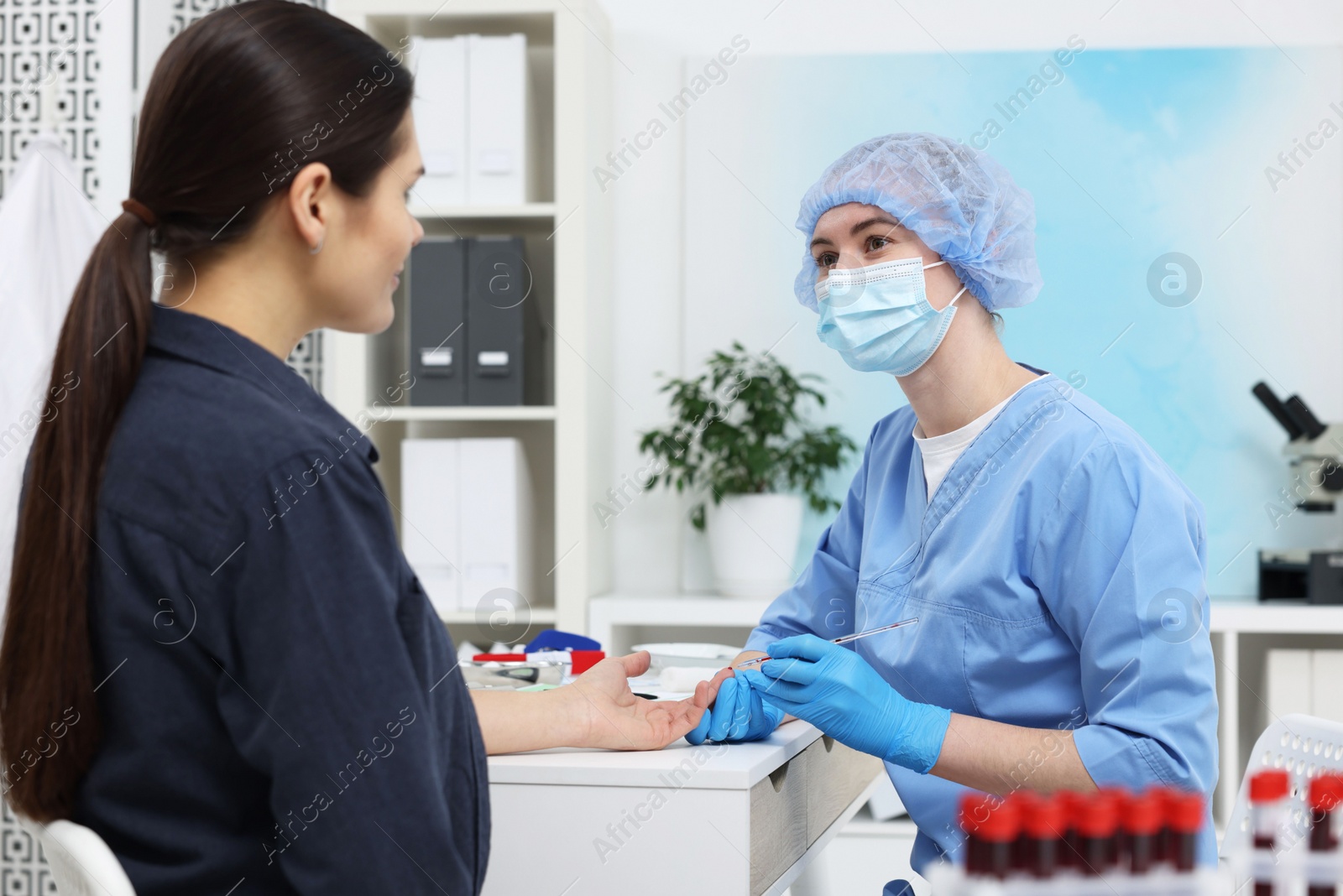 Photo of Laboratory testing. Doctor taking blood sample from patient at white table in hospital