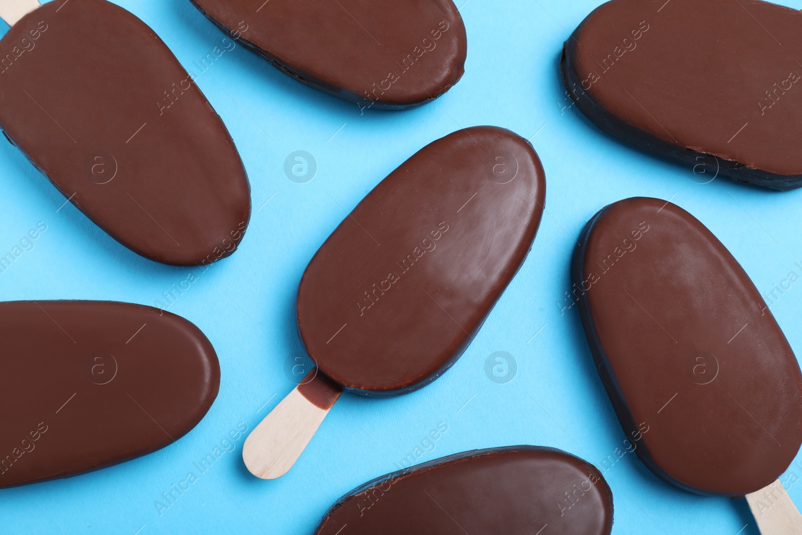 Photo of Glazed ice cream bars in light blue background, flat lay