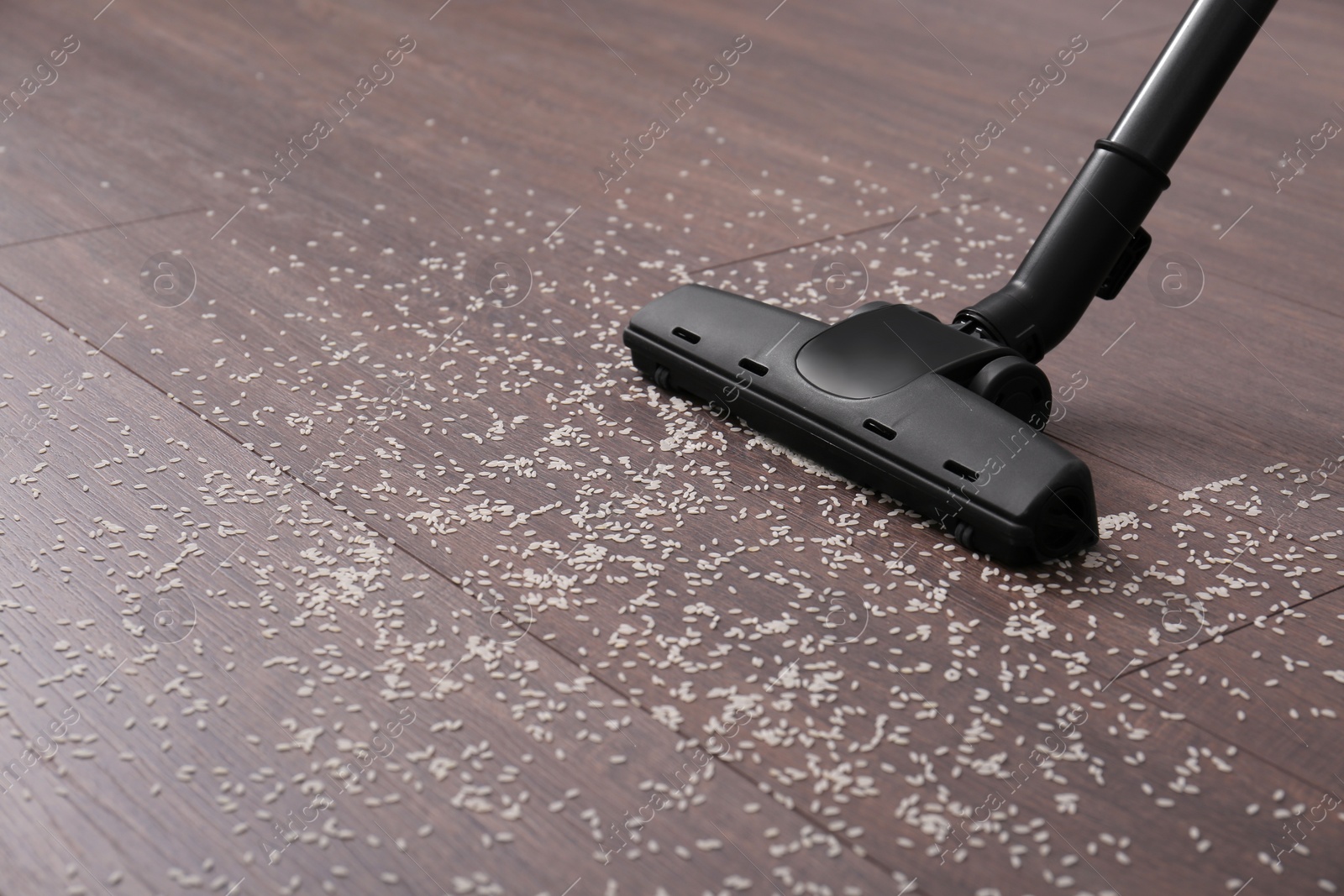 Photo of Vacuuming scattered rice from wooden floor. Space for text