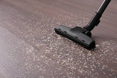 Vacuuming scattered rice from wooden floor. Space for text