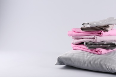 Photo of Stack of clean bed sheets and pillow on white background. Space for text
