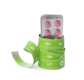 Photo of Weight loss pills and measuring tape on white background