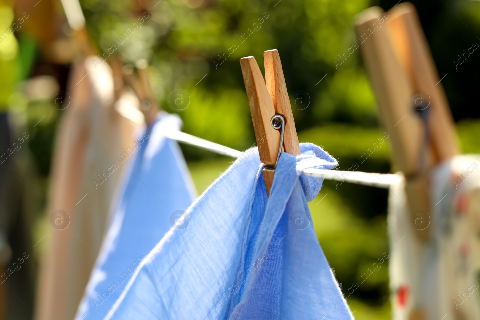 Photo of Clean clothes drying in garden, closeup. Focus on clothespin