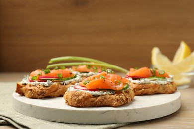 Photo of Tasty canapes with salmon, cucumber, radish and cream cheese on wooden table