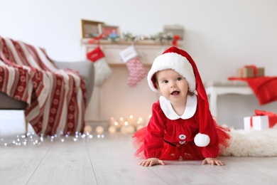 Photo of Cute baby in Christmas costume on floor at home