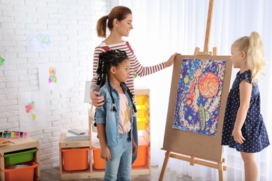 Photo of Children with female teacher at painting lesson indoors