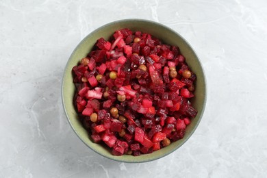 Bowl of delicious fresh vinaigrette salad on light grey marble table, top view